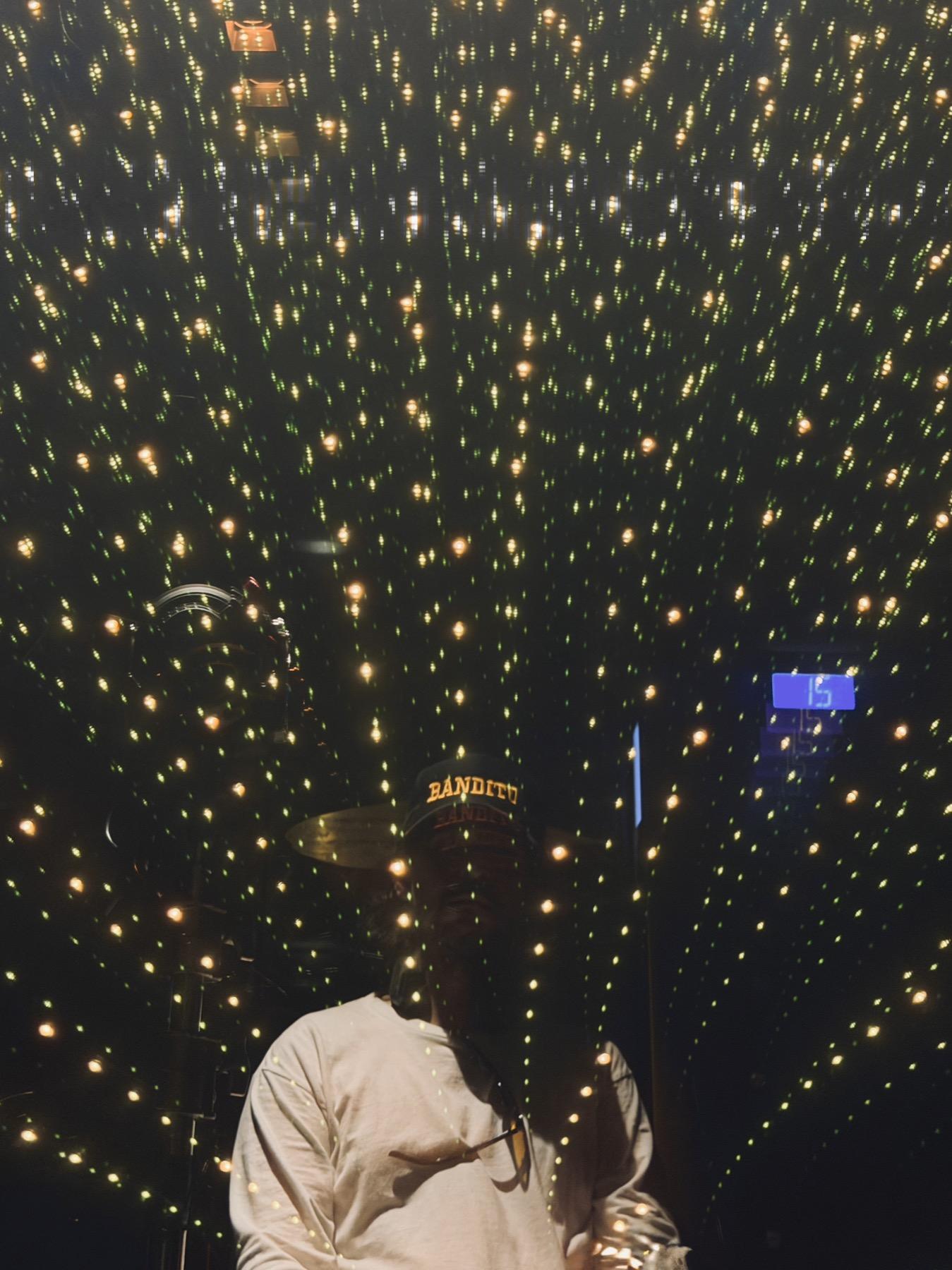 Juandito in a BANDITO cap, reflected among string lights